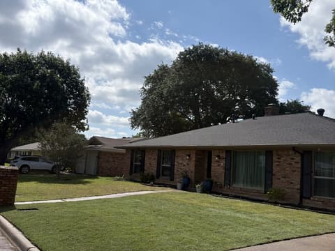 Healthy lawn with clean edges along the driveway of a brick home