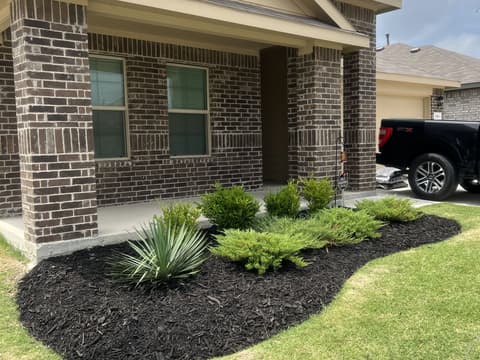 Freshly mulched landscape bed wrapping the corner of a brick home